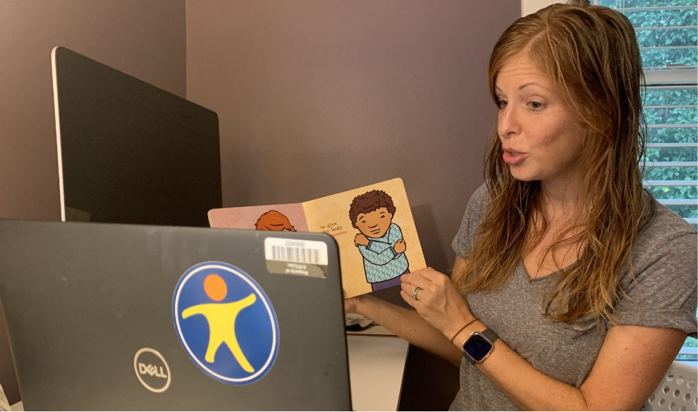 Woman reads book to a child via video conference