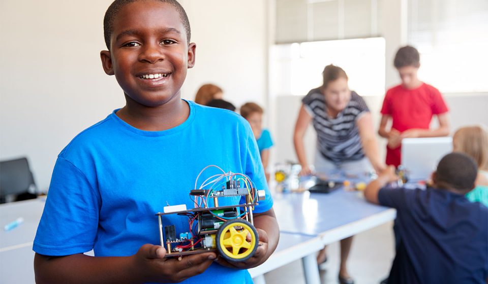 young student with robot vehicle in a school classroom